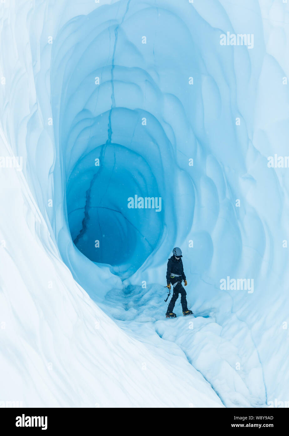 Junge Frau zu Fuß in der Nähe des Eingangs eine große Eishöhle in Alaska. Stockfoto