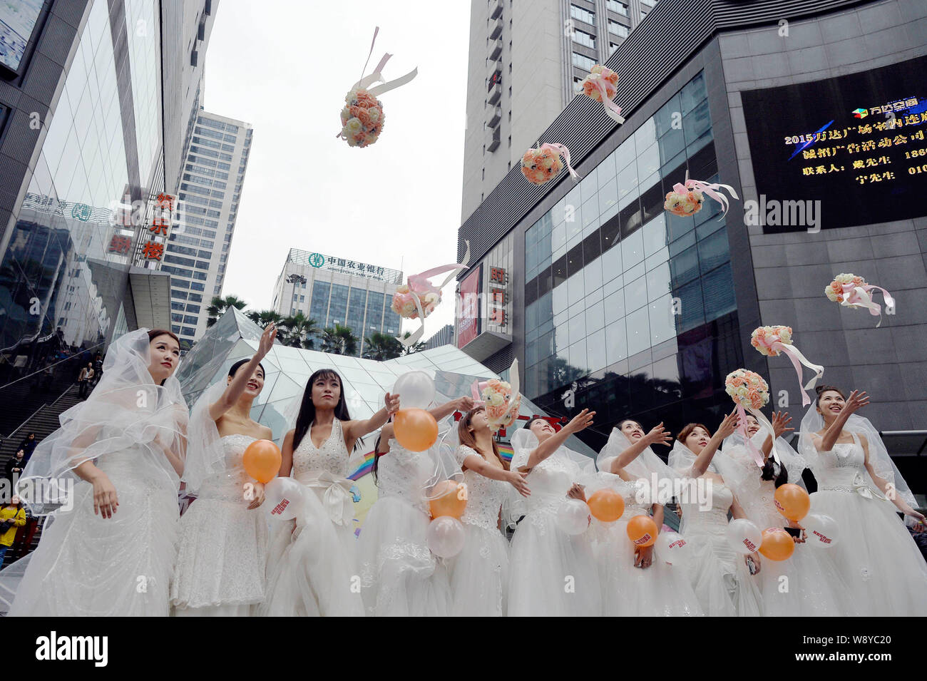 Einzelne Frauen in Hochzeit Kleider gekleidet werfen Blumensträuße in die Luft, bevor Singles Tag am Wanda Square in Chongqing, China, 9. November 2. Stockfoto