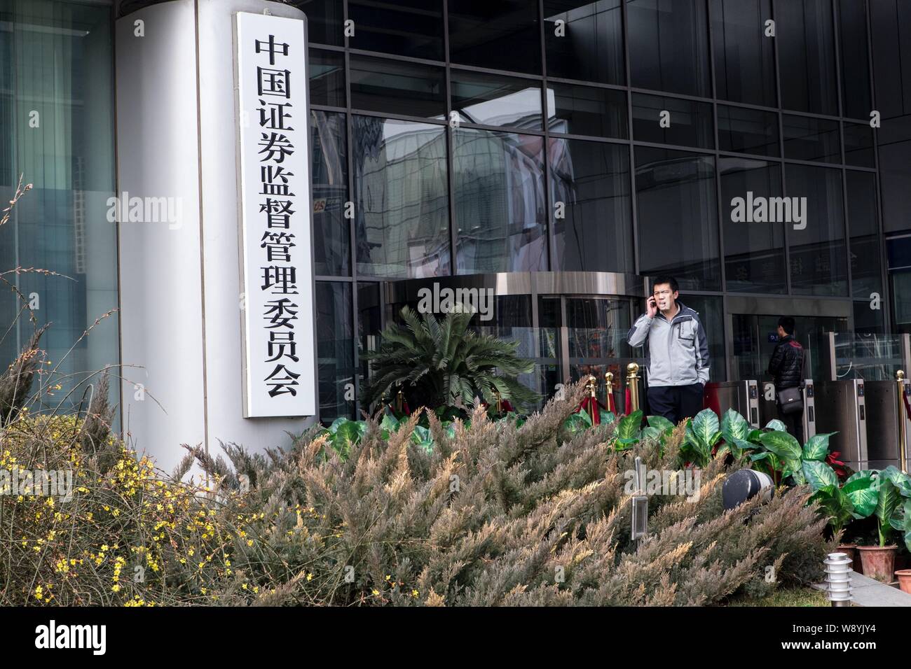 ---- Ein fussgänger Gespräche über sein Handy vor dem Hauptquartier der China Securities Regulatory Commission (CSRC), in Peking, China, 9. Stockfoto