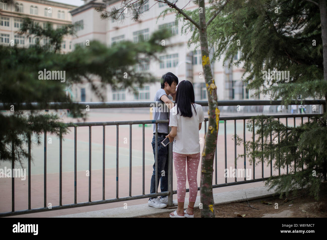 Zwei chinesische Studenten, die scheinen, ein Liebespaar zu sein, sprechen Sie mit jedem Anderen heimlich auf dem Spielplatz am Lanxiang Berufliche Schule als Liebe ist verboten Stockfoto