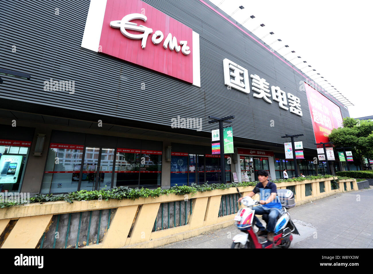 ---- Ein Radfahrer fährt hinter einem gome Home Appliance Store in Shanghai, China, 12. September 2014. Chinesische Haushaltsgeräte und Elektronik Händler Gom Stockfoto