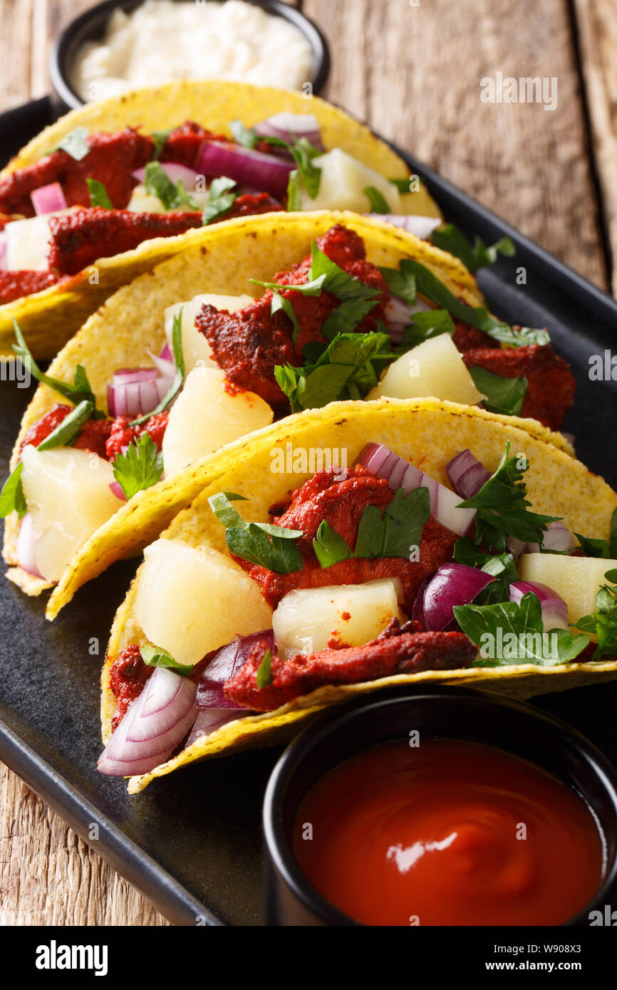 Tacos al Pastor mit Schweinefleisch, Ananas, Zwiebeln und Kräuter close-up auf einem Teller auf den Tisch. Vertikale Stockfoto