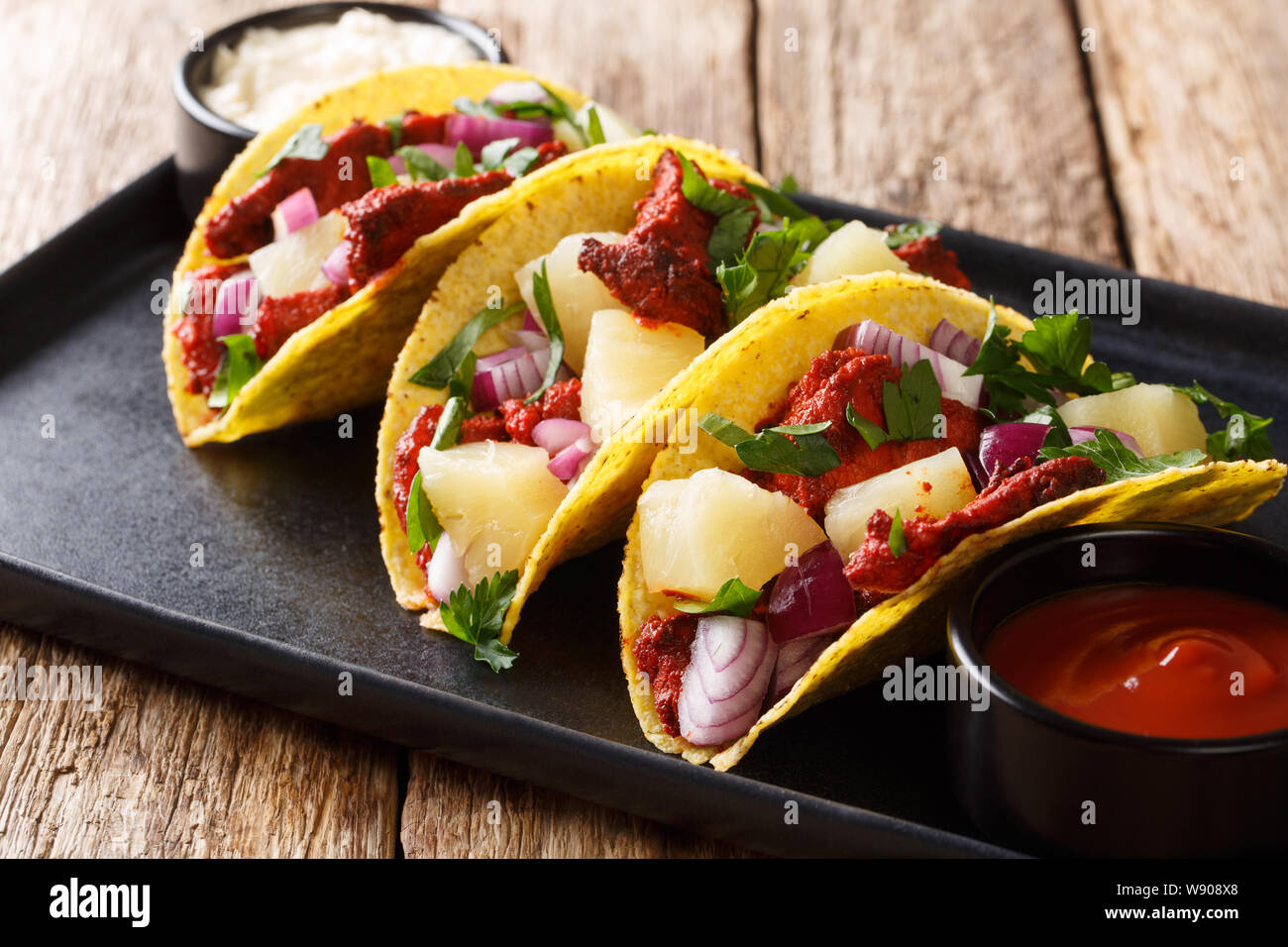 Mexikanische Tacos al Pastor, serviert mit Sauce closeup auf einem Teller auf den Tisch. Horizontale Stockfoto