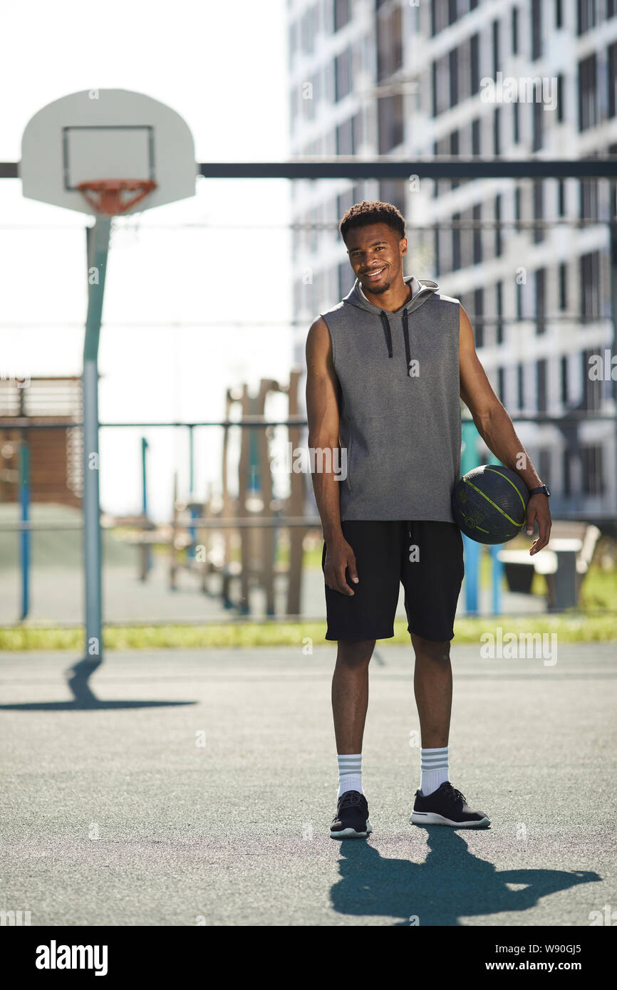 In voller Länge Porträt der Afrikanischen basketball Player steht die Hoop im Freien Gericht und lächelnd an Kamera, kopieren Raum Stockfoto