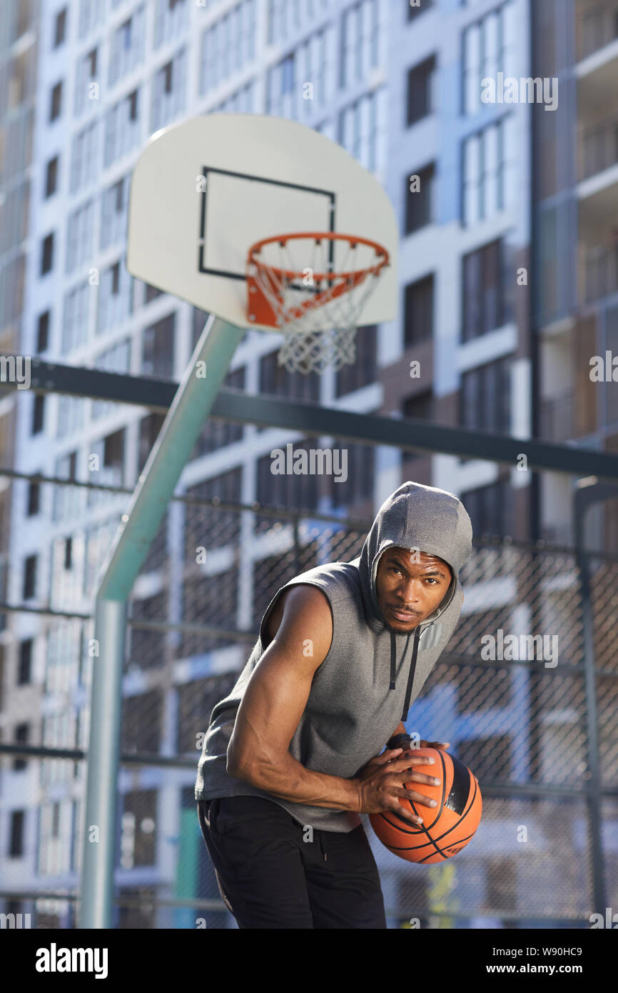 Portrait der muskulösen Basketballspieler an Kamera holding Ball im Freien Gericht suchen, Action Shot Stockfoto