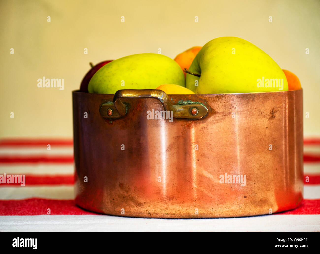 Äpfel, Pflaumen und Aprikosen in alten kupfernen Topf und hölzerne Schüssel auf dem Hintergrund Stockfoto