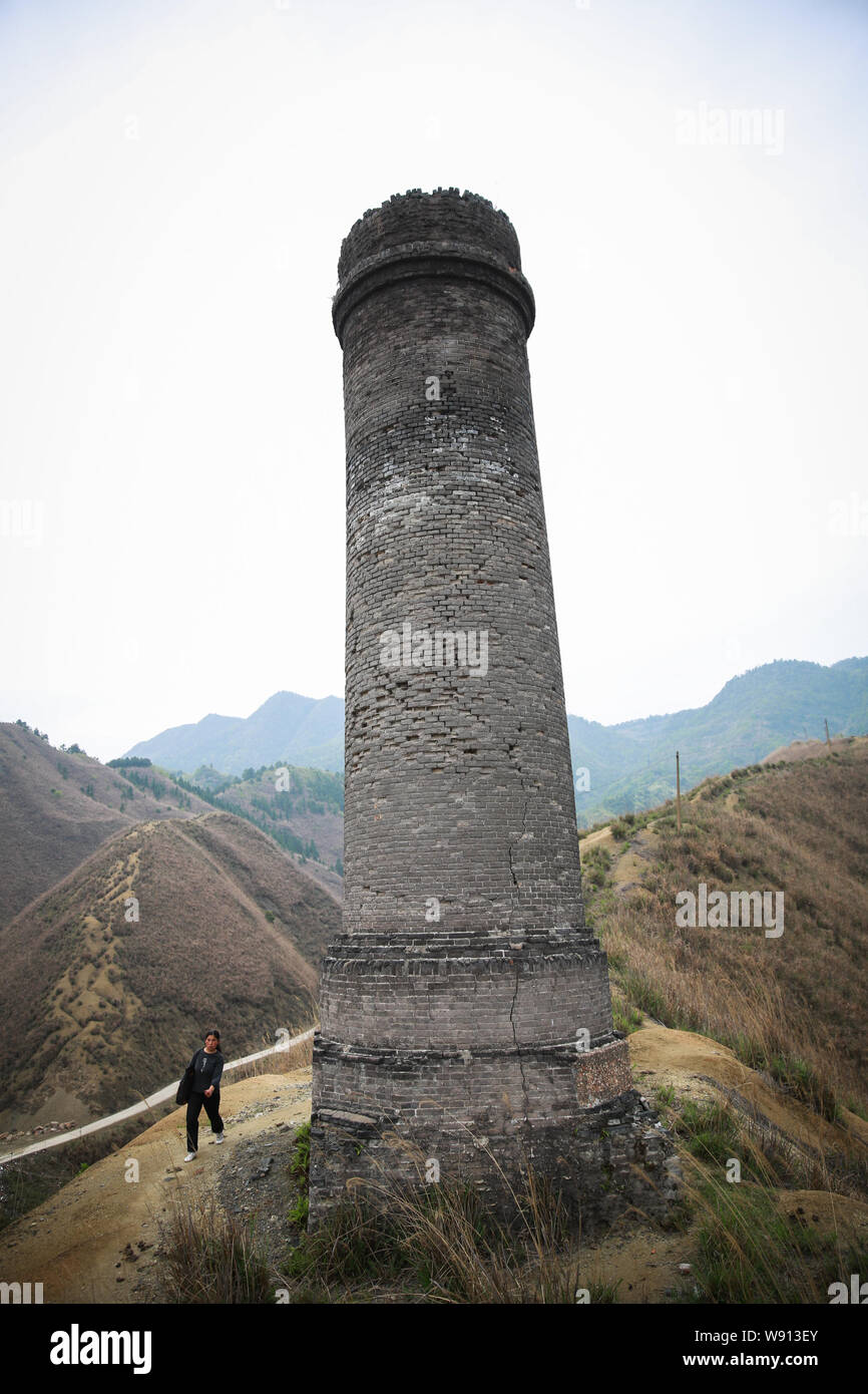 Ein chinesischer Dorfbewohner Spaziergänge hinter einem Schornstein für Arsen Raffination in Heshan Dorf, Shimen Grafschaft, der Stadt Changde, Zentrale China Provinz Hunan, 1. April 20. Stockfoto
