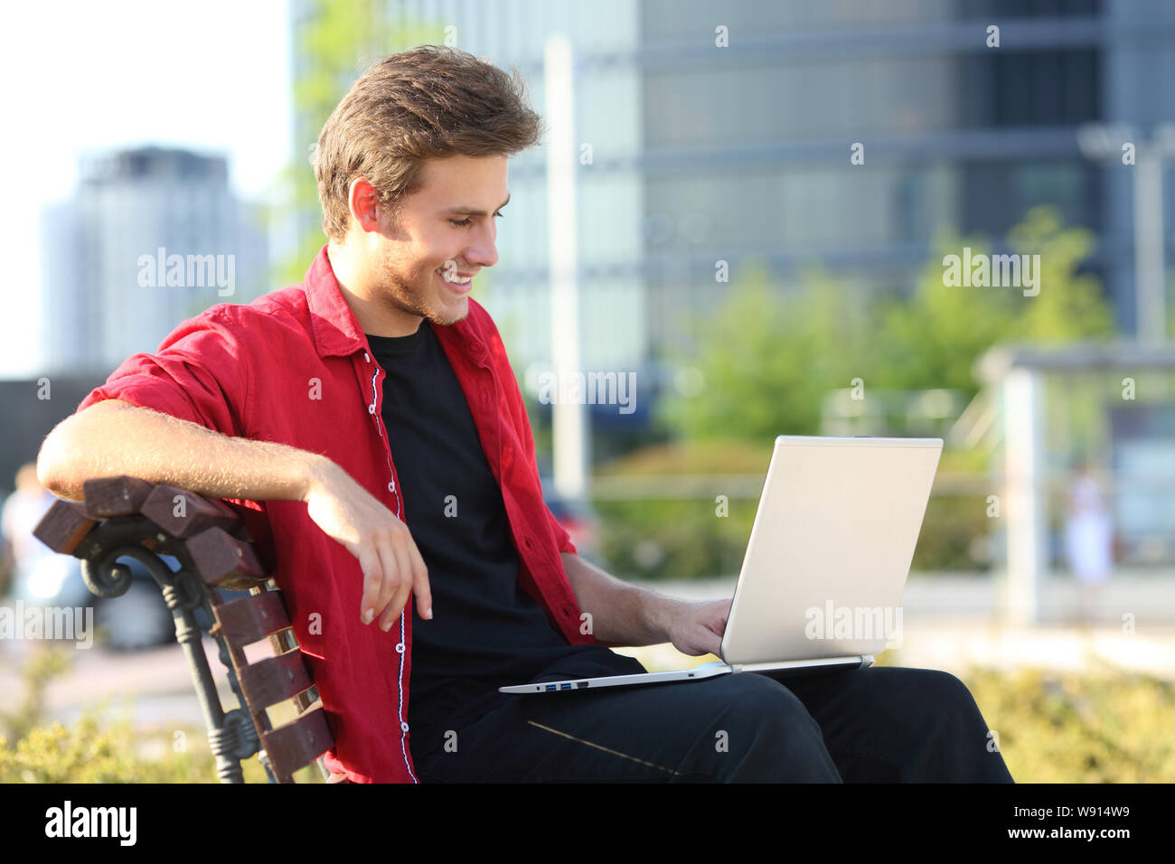 Glückliche Menschen sitzen auf einer Bank mit einem Laptop online Videos in einem Park zu beobachten Stockfoto