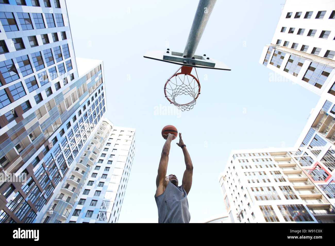 Low Angle Shot Aktion der Afrikanischen basketball Player schießen Slam Dunk gegen Himmel im städtischen Hintergrund, kopieren Raum Stockfoto