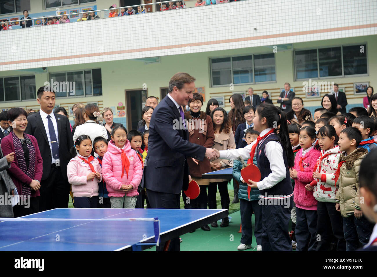 Der britische Premierminister David Cameron, Mitte, schüttelt Hände mit einer jungen chinesischen Studenten nach Tischtennis spielen mit ihr bei seinem Besuch in einem prim. Stockfoto