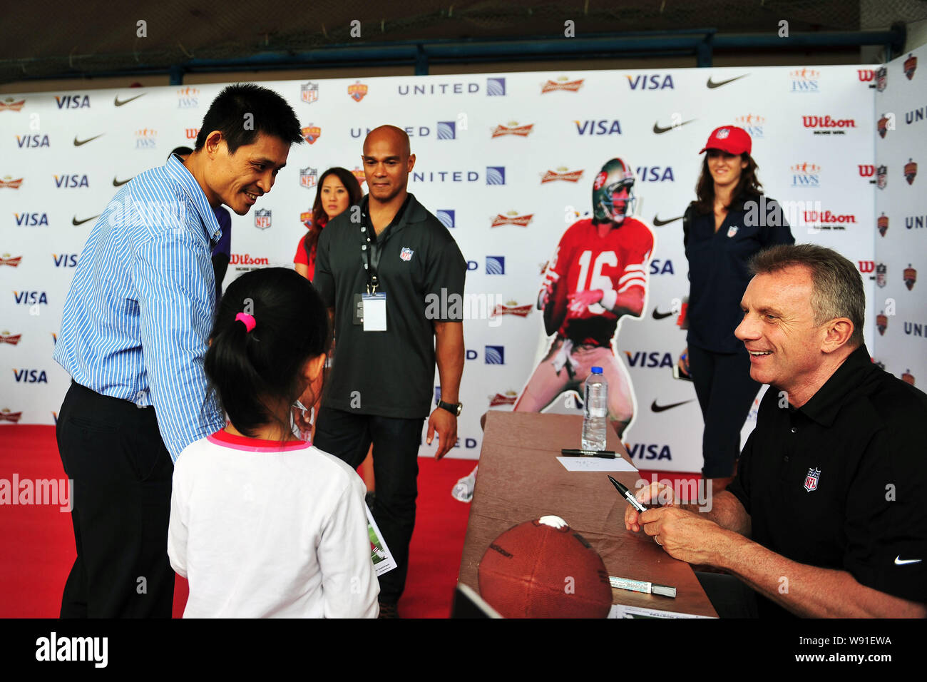 Ehemalige professionelle American football player Joe Montana, rechts, lächelt nach Autographierend für eine junge chinesische Ventilator während einer Werbeveranstaltung für Ame Stockfoto