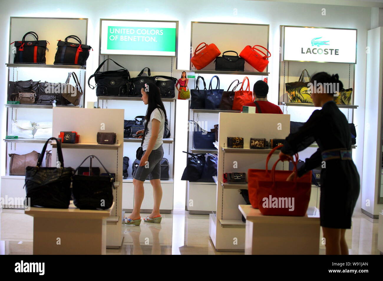 ------ Kunden im Beutel zu einem Fashion Store von Lacoste in Sanya, China Hainan Provinz betrachten, 24. November 2011. Einige Chargen von Kleidung, die von der Stockfoto