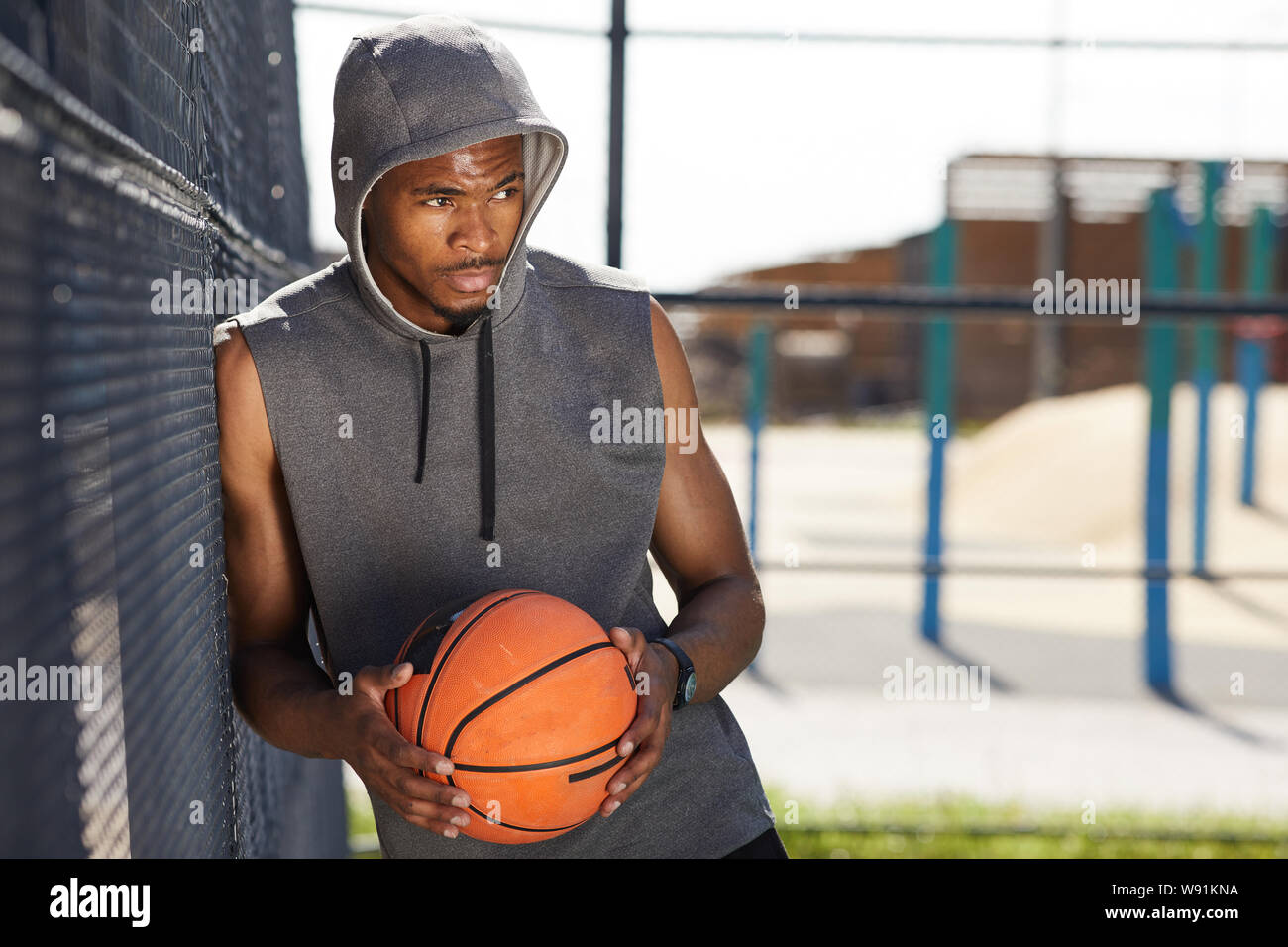Taille bis Porträt des zeitgenössischen afroamerikanischen Mann mit Basketball Ball in Sportplatz im Freien Raum darstellen, kopieren Stockfoto
