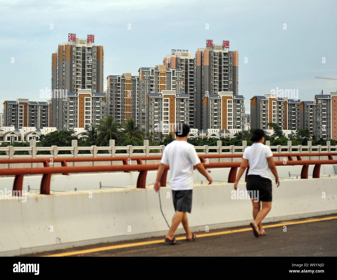 Lokale Bürger Spaziergang, vorbei an einem neuen Wohngebiet Apartment Projekt in Qionghai, South China Hainan Provinz, 16. Juli 2013. Die Preise von neuen und existin Stockfoto