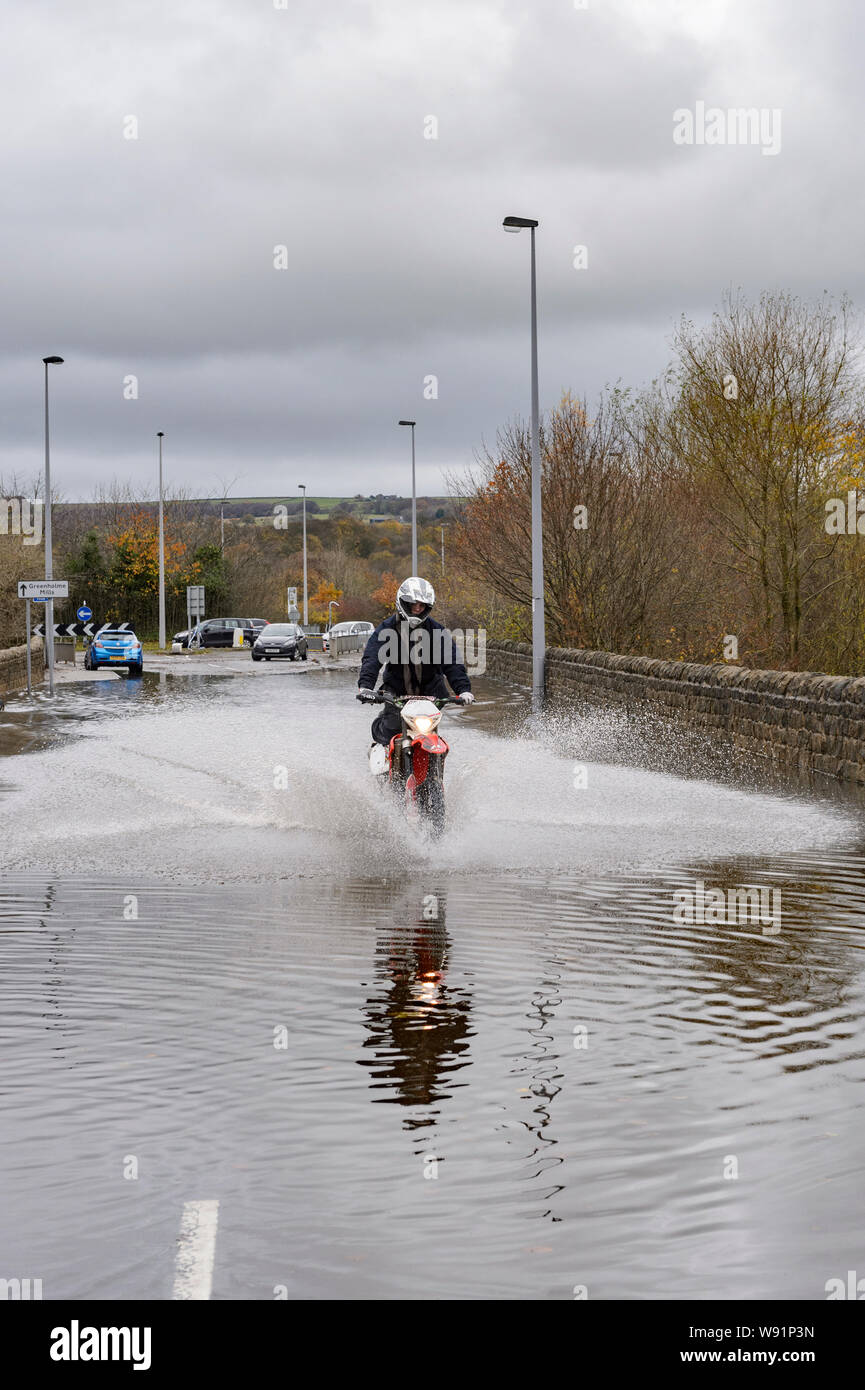 Überschwemmung - motorradfahrer Reiten (Spritzwasser) Motorrad in Hochwasser auf überschwemmten Straßen, unpassierbare zu Autos - Burley in Bösingen, Yorkshire, England, Großbritannien Stockfoto