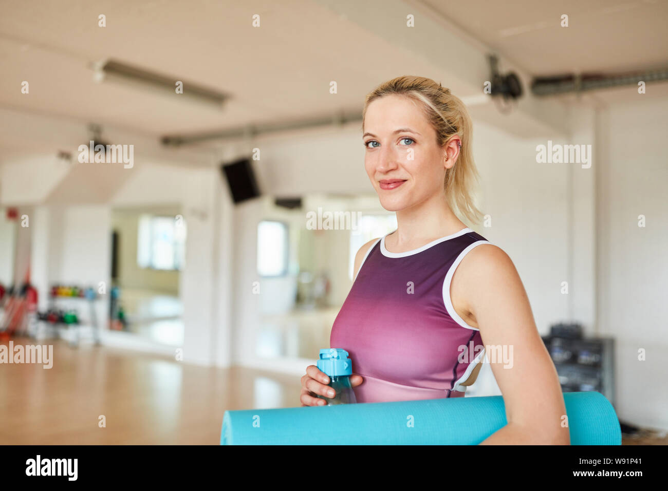 Frau mit Yoga Matte in Fitnesscenter yoga Klasse Stockfoto