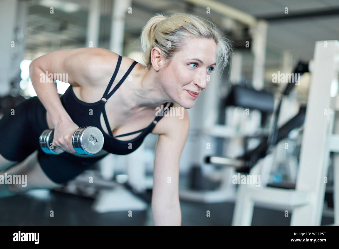 Junge Frau Aufzüge Hantel während Stärke Training im Fitness Center Stockfoto