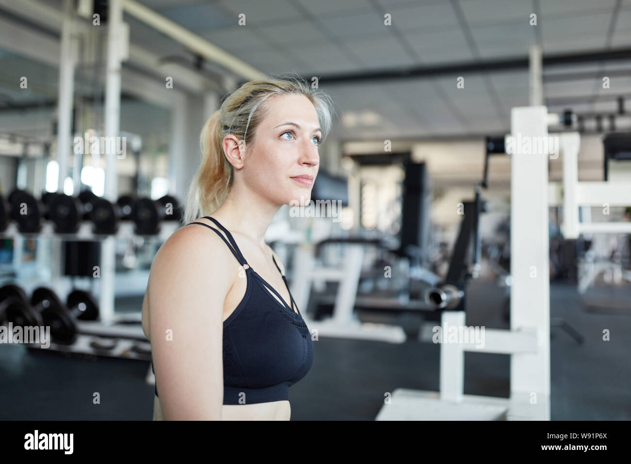 Sportliche junge Frau im Fitnesscenter Tagträumen während einer Pause Stockfoto