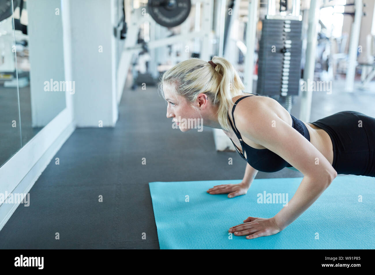 Sportliche junge Frau tut, Push-ups auf der Yogamatte im Fitnesscenter Stockfoto