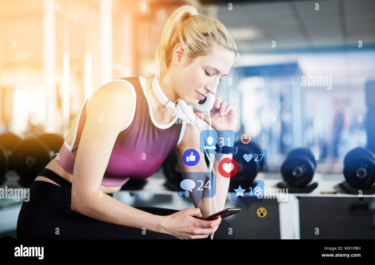 Junge Frau gibt Bewertung auf dem Smartphone beim Trainieren im Fitnesscenter Stockfoto