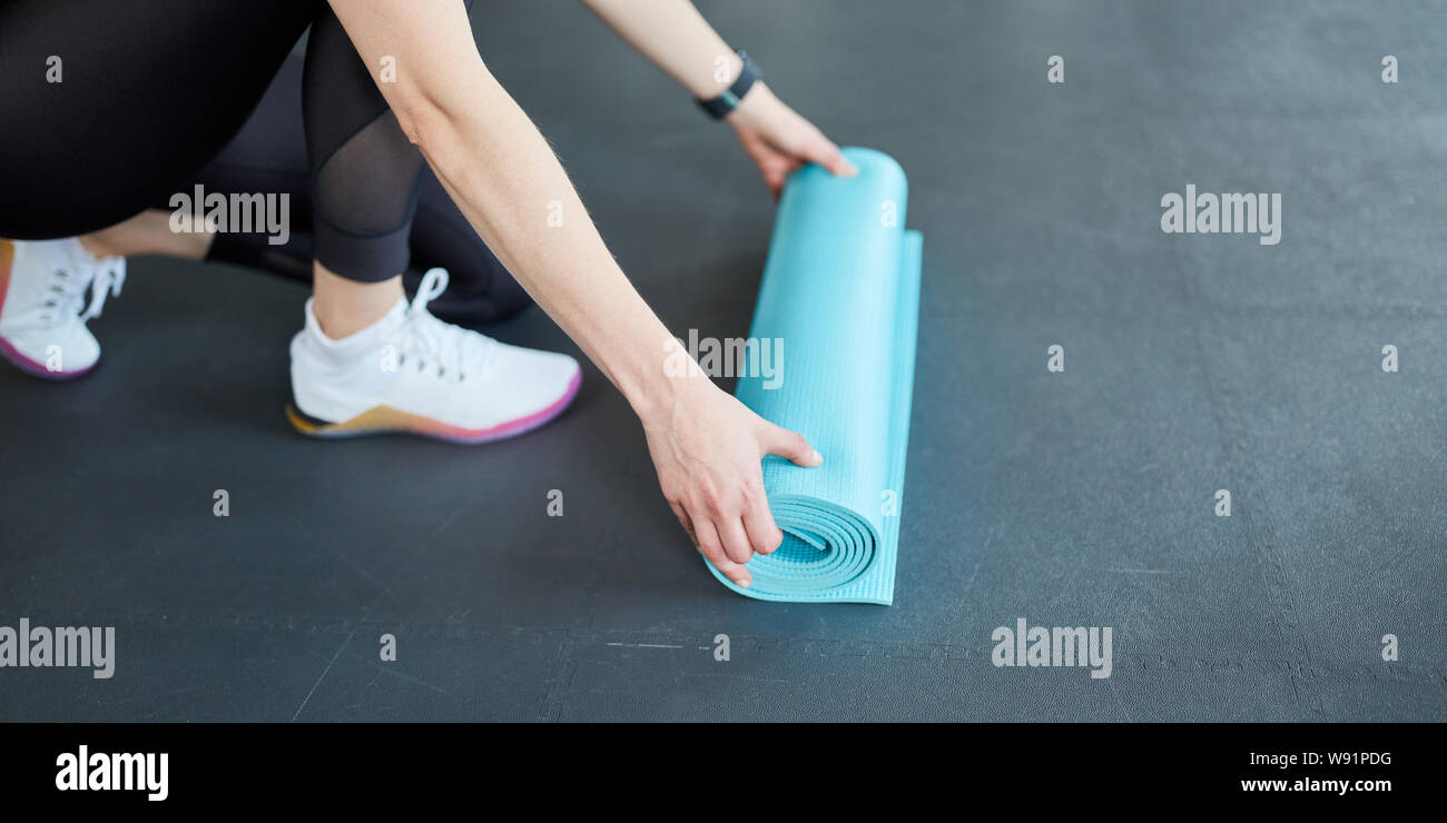 Junge Frau rollt eine Yogamatte nach Fitness Workout Stockfoto