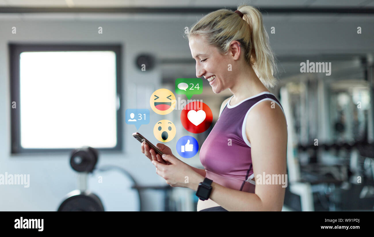 Junge Frau als soziale Medien mit Smartphones im Fitnesscenter Einflussnehmer Stockfoto