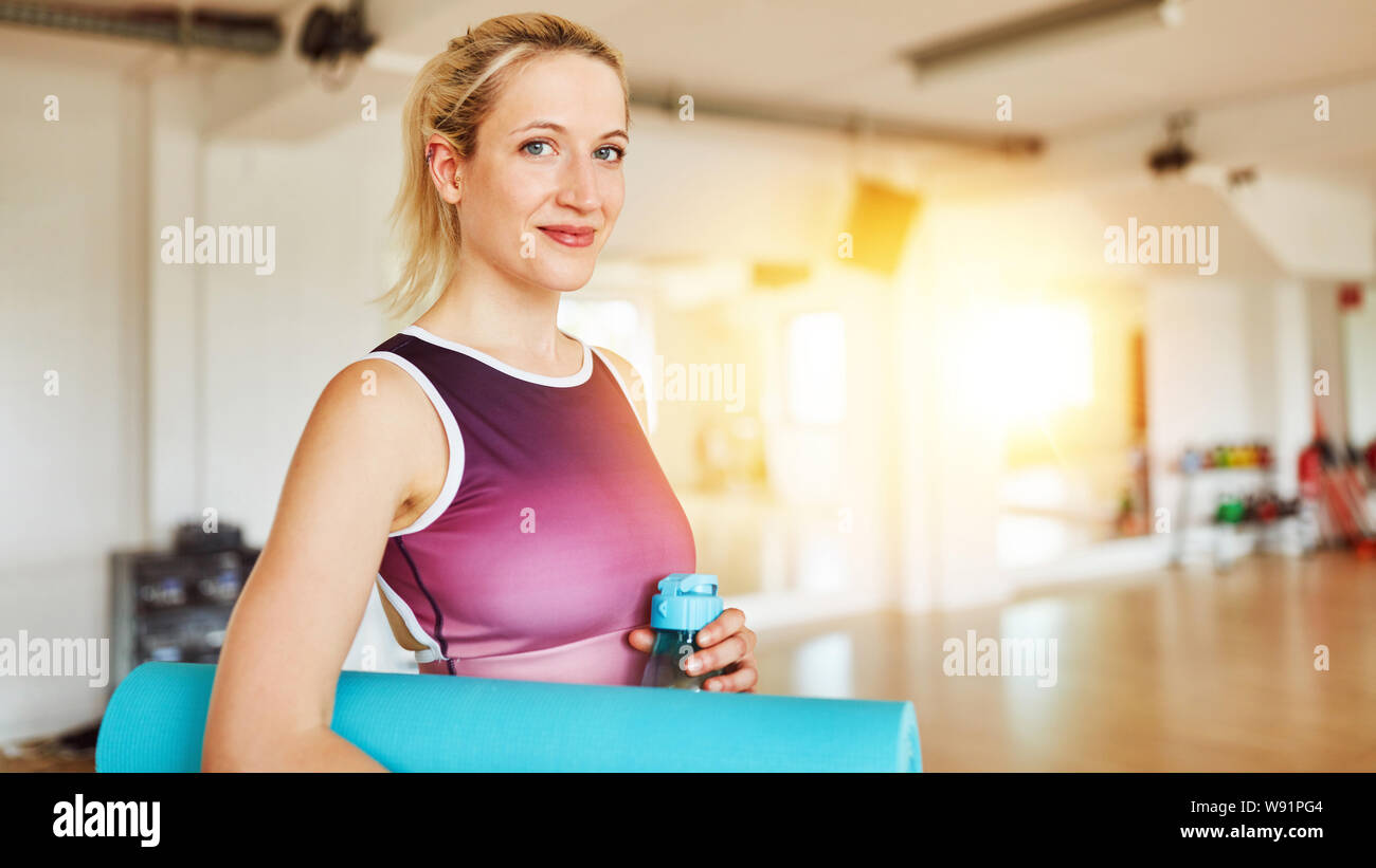 Frau mit Yoga Matte im Klassenzimmer der Fitnesscenter vor dem Training Stockfoto