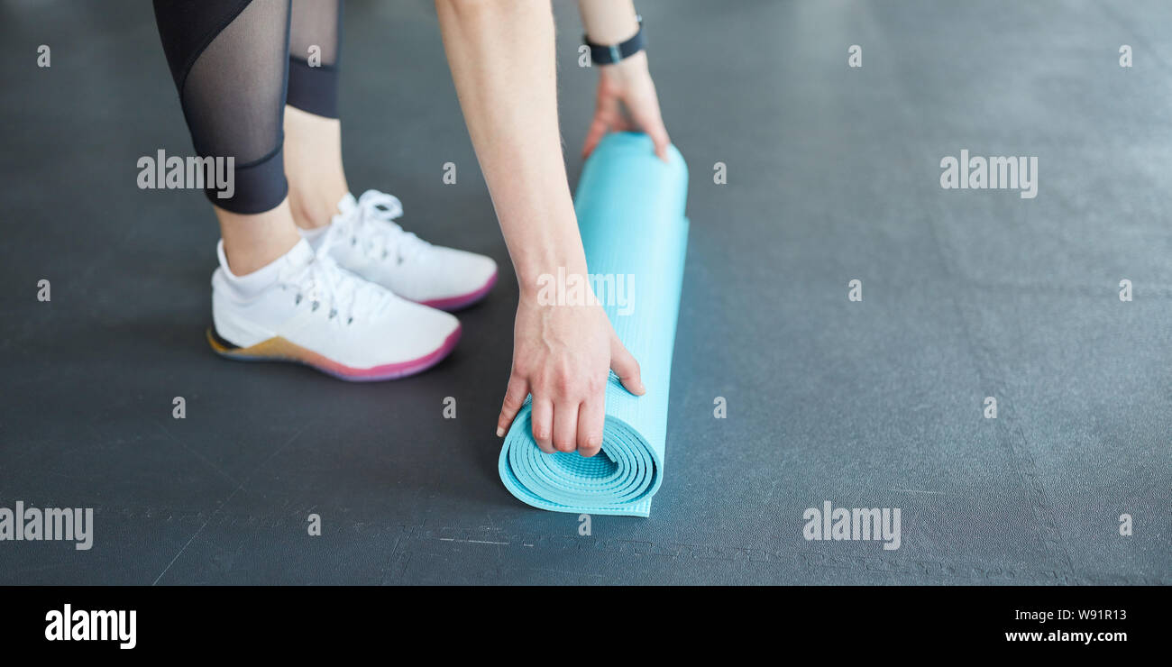 Frau rollt eine Yoga Matte zusammen nach Fitness oder Fitnessstudio Workout Stockfoto