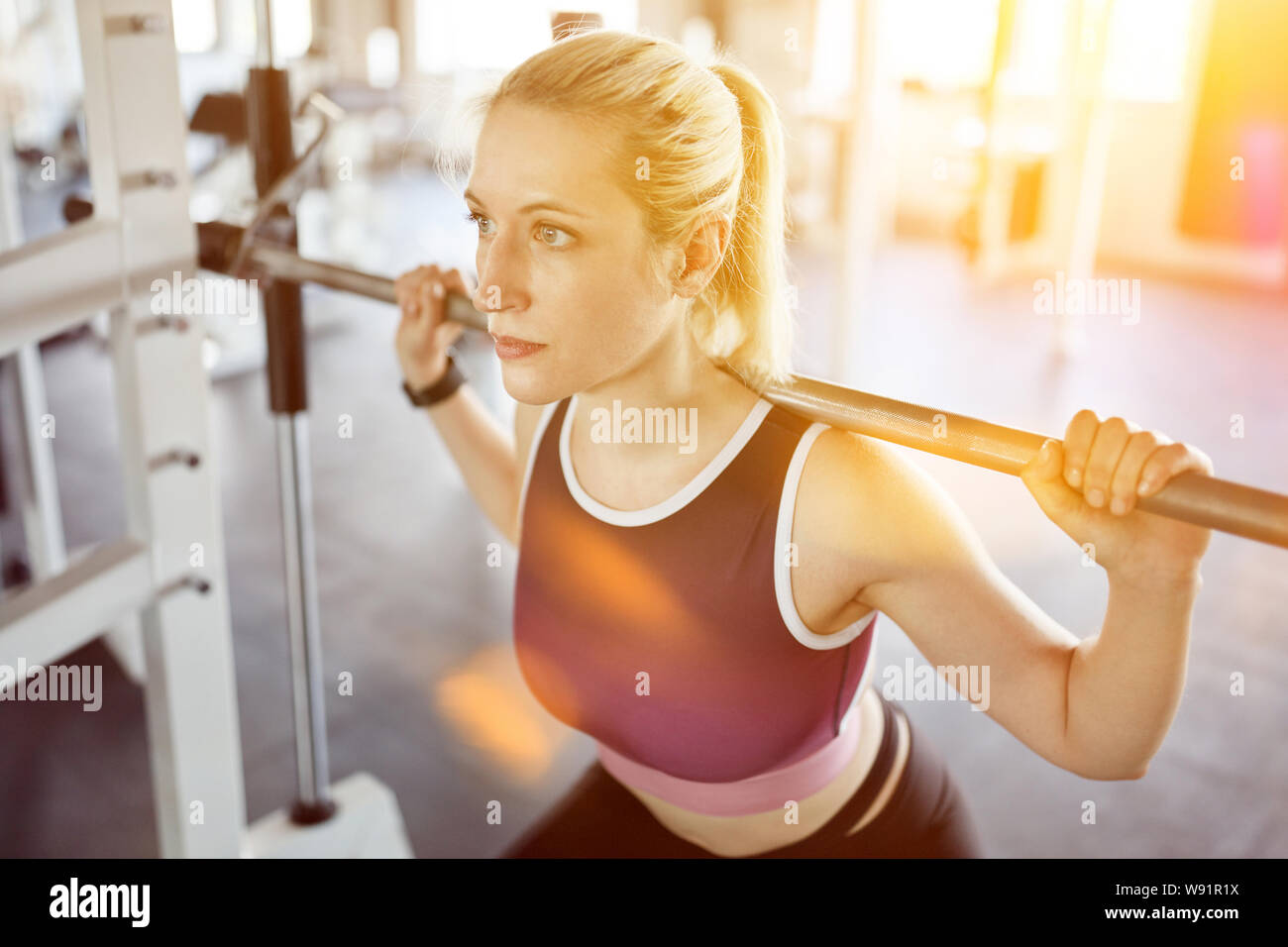 Junge Frau, Gewichte zu heben mit Langhantel im Fitness Center Stockfoto