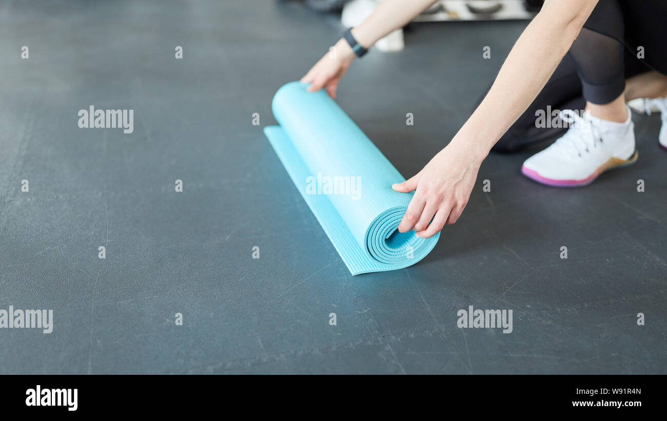 Junge Frau rollt eine Yoga Matte im Fitnesscenter vor dem Training Stockfoto
