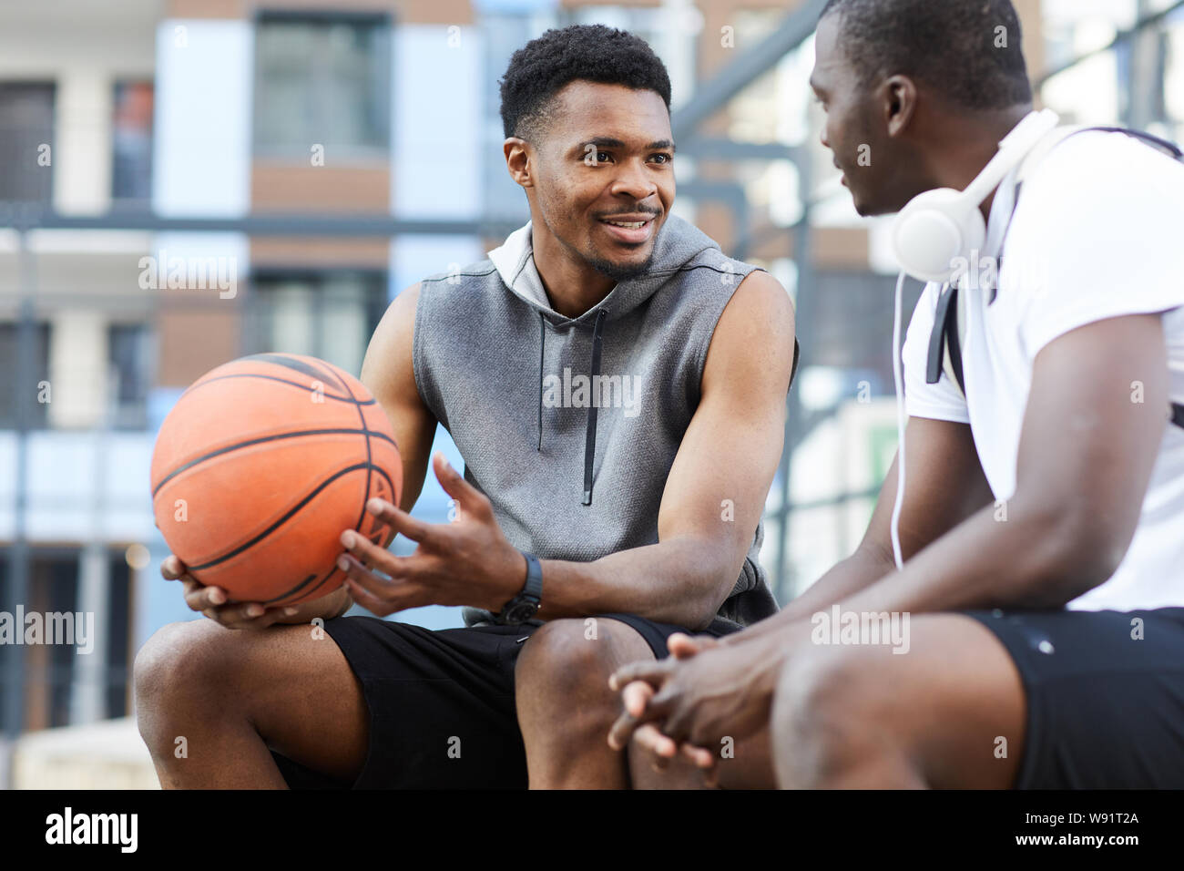 Porträt von zwei Afro-amerikanische Jungs chatten sitzen auf Basketball im freien Platz kopieren Stockfoto