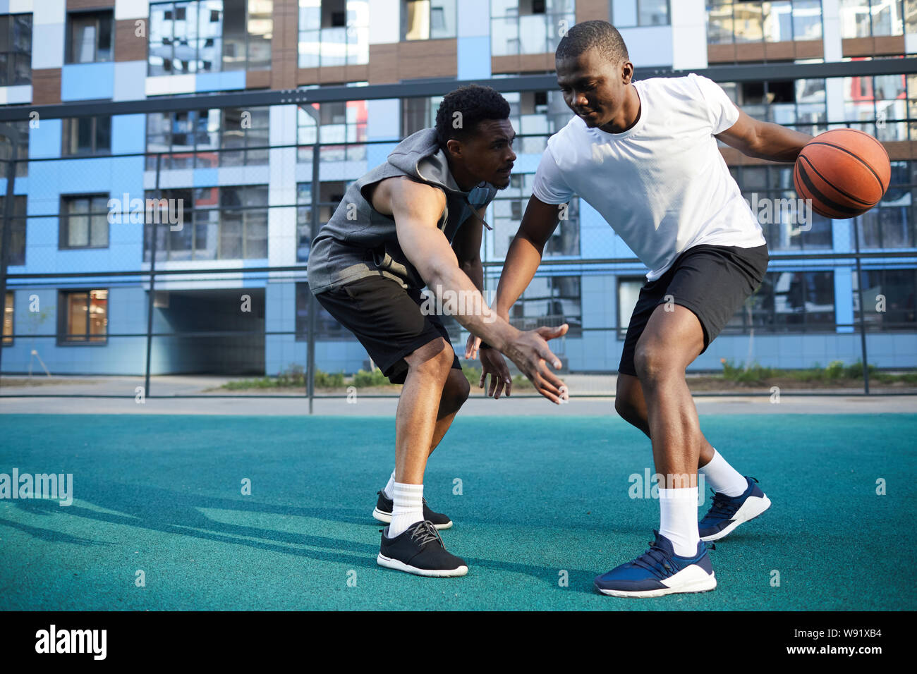 Volle Länge Aktion Schuß von zwei muskulöse Afrikanische Mann spielt Basketball im freien Platz kopieren Stockfoto