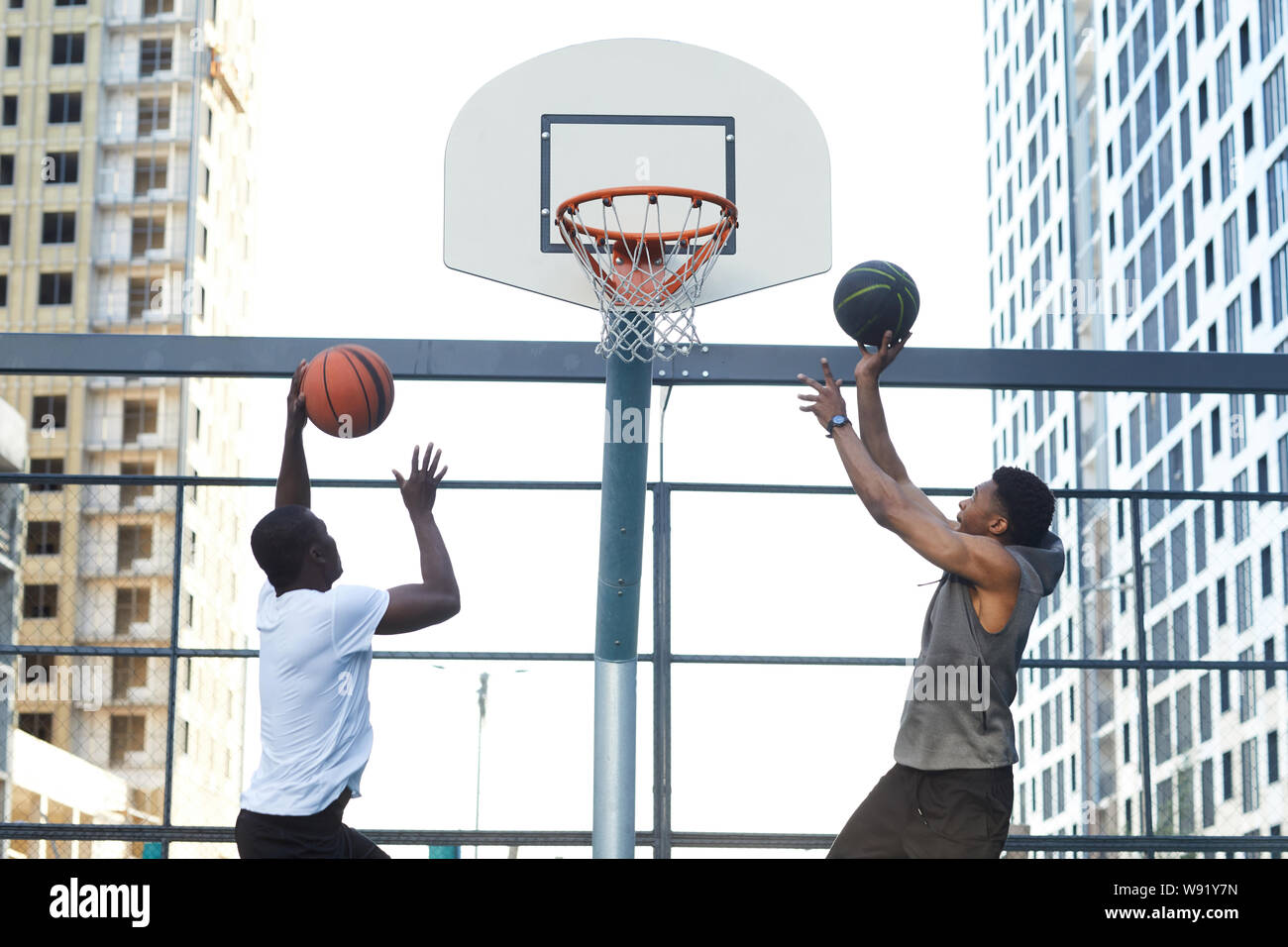 Zurück Blick auf zwei sportliche afroamerikanische Männer Basketball spielen im städtischen Raum einstellen, kopieren Stockfoto