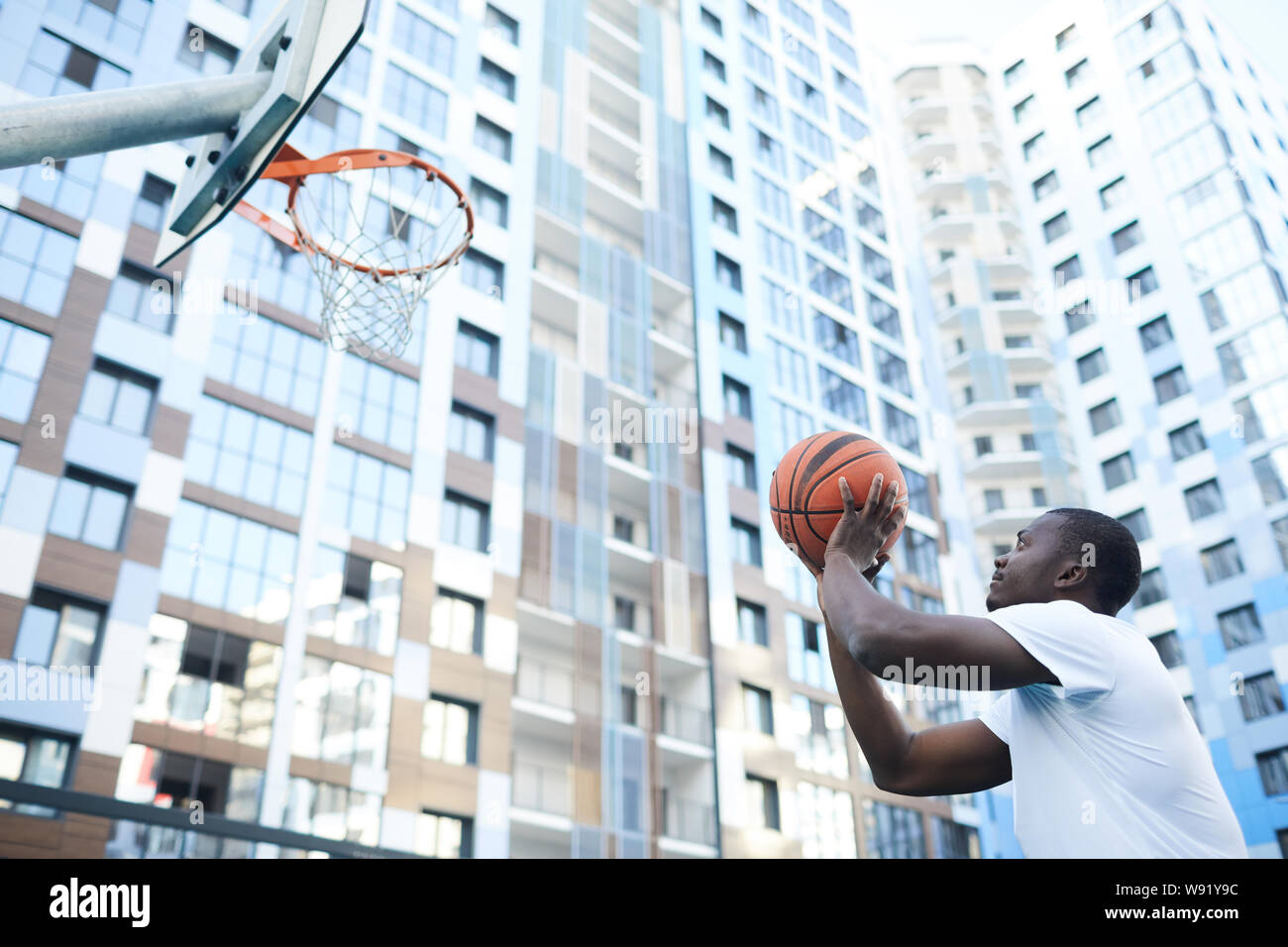 Portrait von sportlichen Afrikaner - Mann wirft Ball am Hoop beim Basketball spielen in städtischen Umgebung, kopieren Raum Stockfoto