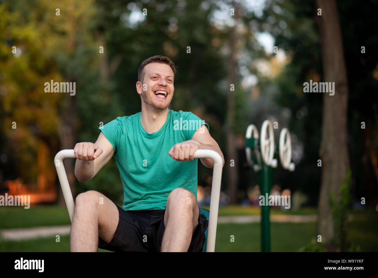 Schöner mann Training im Fitnessbereich im Freien am Rudergerät Stockfoto