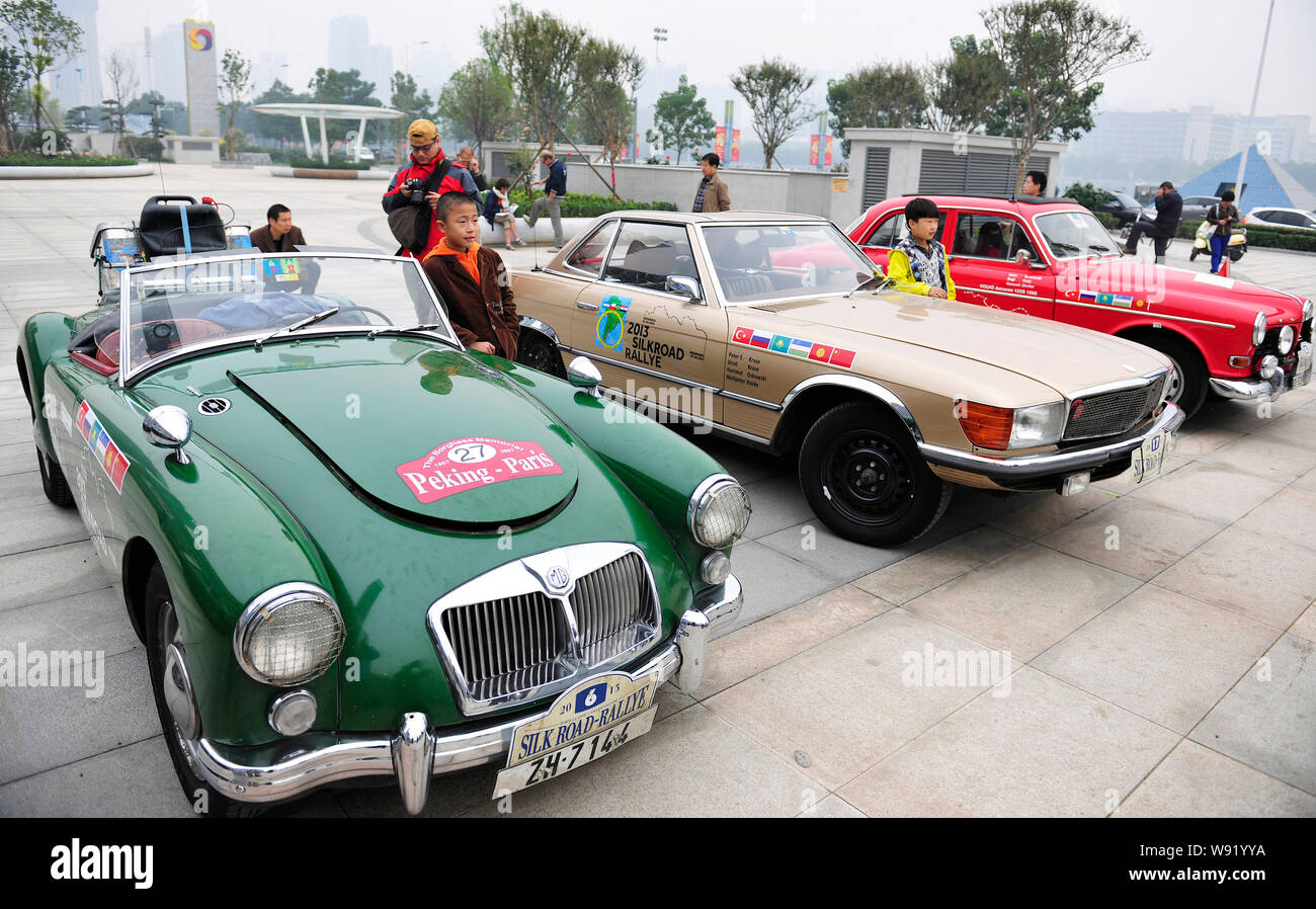 Junge chinesische Besucher posieren mit Old Timer Autos von MG und andere Marken, die 2013 Silk Road Rallye während einer Ausstellung an Quanshun erreicht haben Stockfoto