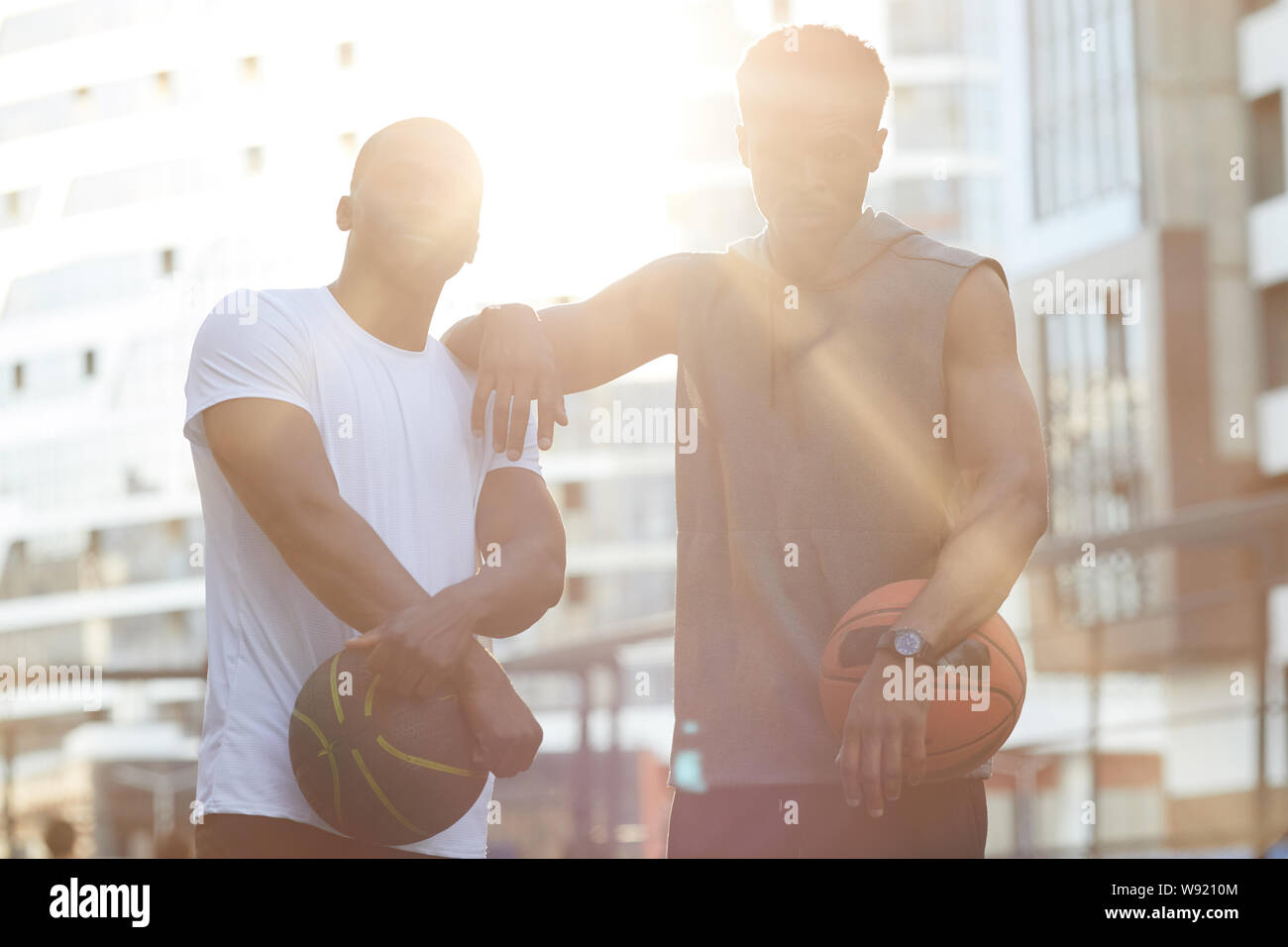 Taille bis Portrait von zwei schöne afrikanische Männer in Basketball im freien Stellen, die durch Sonnenlicht beleuchtet Stockfoto