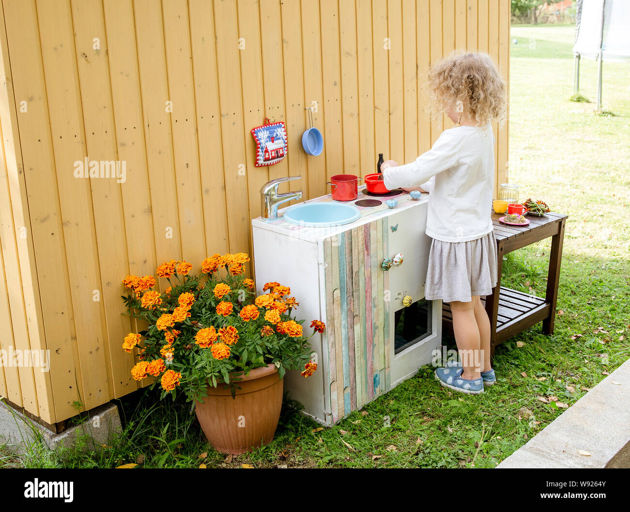 Mädchen spielen im Freien in sogenannten Schlamm Küche, wo Sie gefälschte Essen, Spielen mit Sand, Erde, Wasser, Pflanzen machen können und einen Dreck machen. Stockfoto