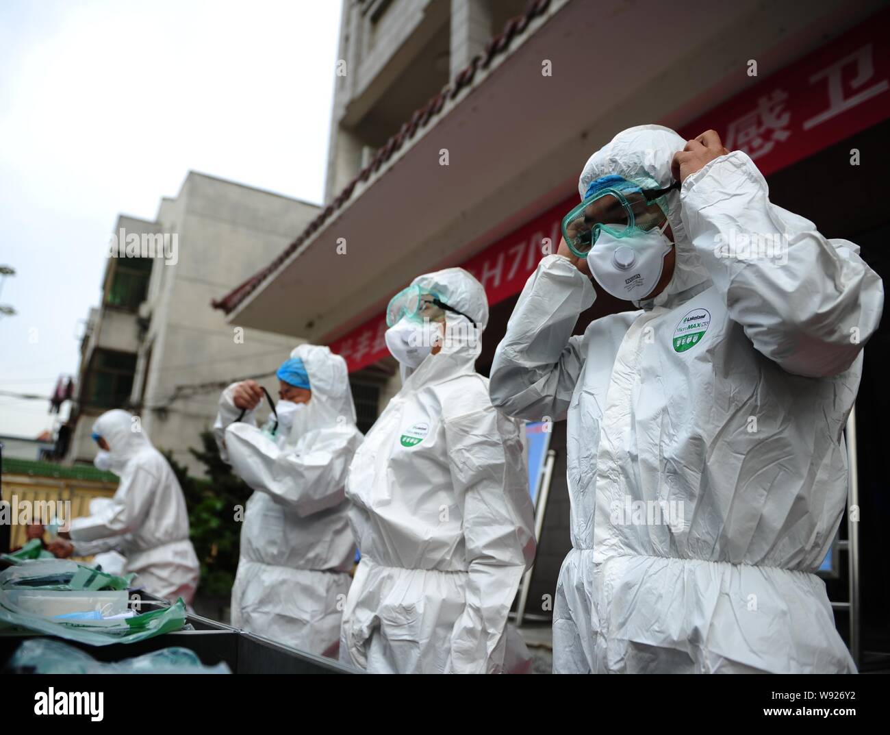 Chinesische Arbeiter aus der lokalen Zentrum für die Prävention und die Kontrolle von Krankheiten, schützende Kleidung, auf Gläser während einer Räumungsübung gegen die Uhr 7. Stockfoto