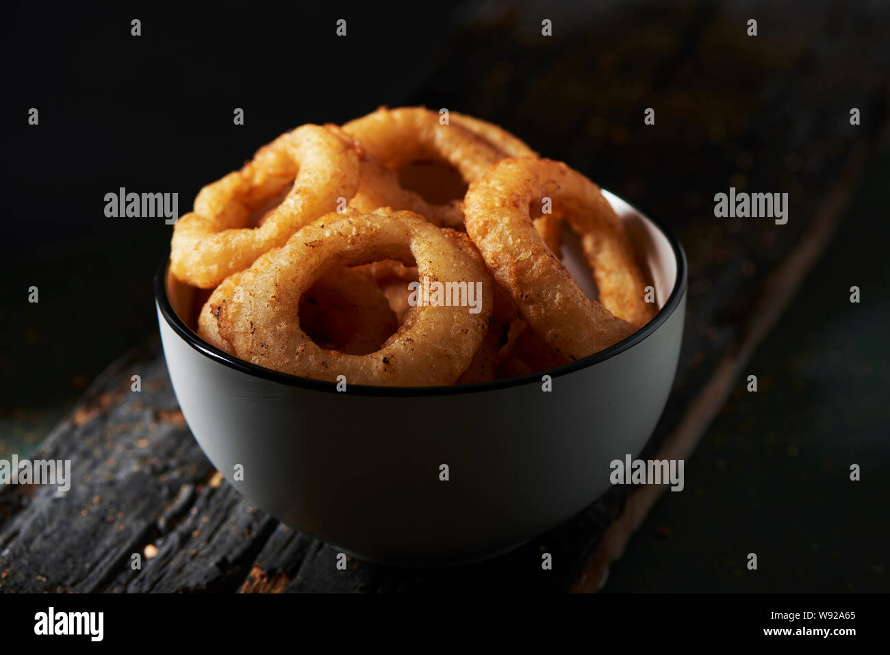 Nahaufnahme von einem weißen Keramik Schüssel mit calamares a la Romana, gebratene zerschlagene Tintenfischringe typisch für Spanien, auf einem dunklen rustikalen Holztisch Stockfoto