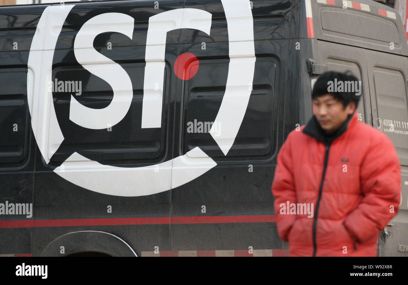 ---- Ein Fußgänger geht hinter einem van der SF Express in Qingdao Stadt, East China Provinz Shandong, 26. März 2012. Chinesische Private Equity Firma Citic Stockfoto