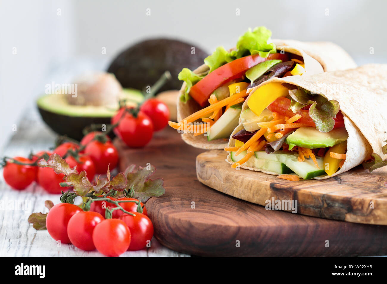 Ein gesundes Mittag- oder Abendessen für eine vegane/vegetarische Wrap mit argula Salat gemacht, in Scheiben geschnittene Tomaten, Gurken, Avocado, Paprika und Karotten. Stockfoto