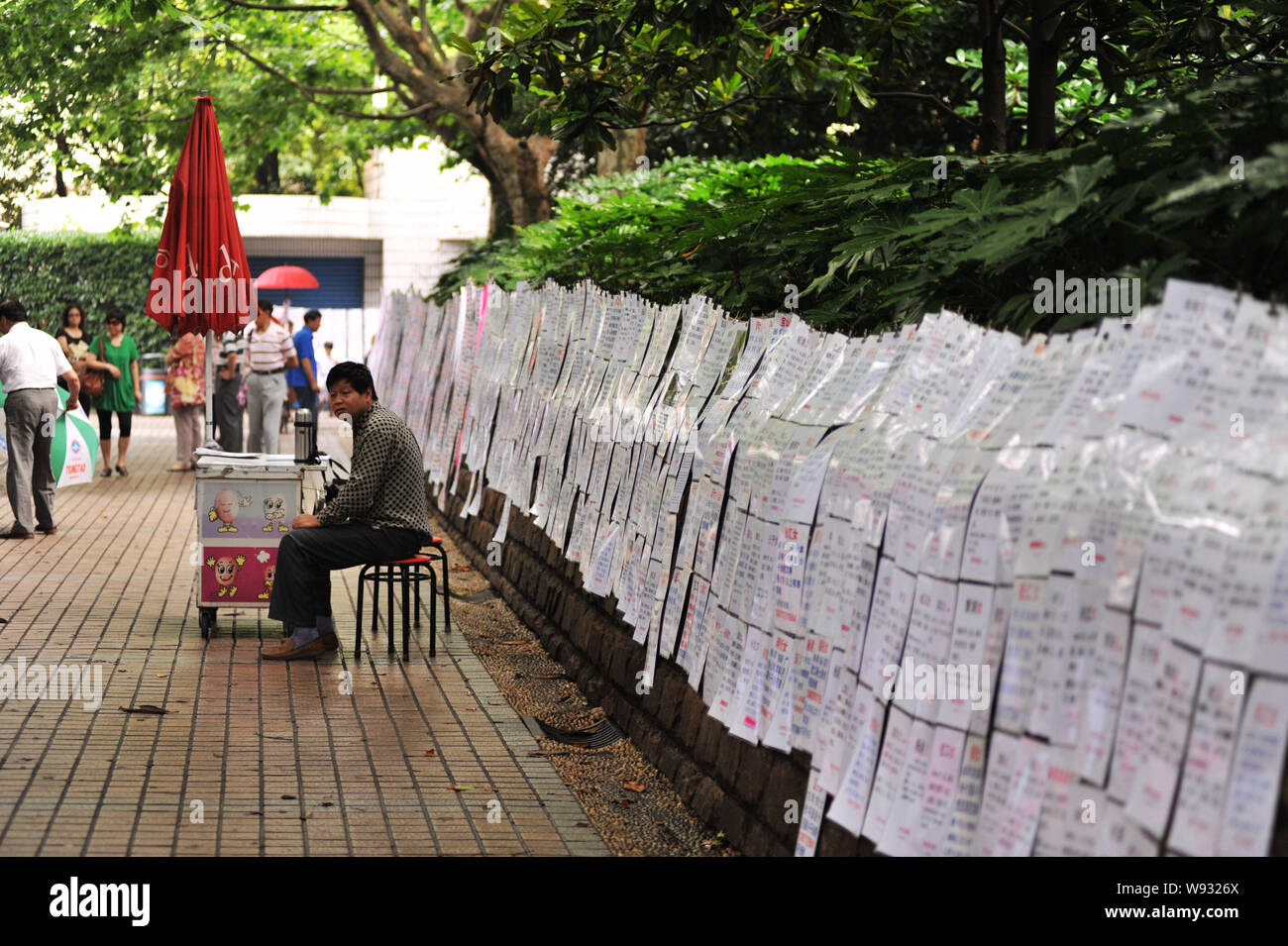 Leute schauen auf Stücke von Kontaktinformationen auf dem Heiratsmarkt in Shanghais Völker Platz in Shanghai, China, 30. Juni 2013. Die Ehe Marke Stockfoto