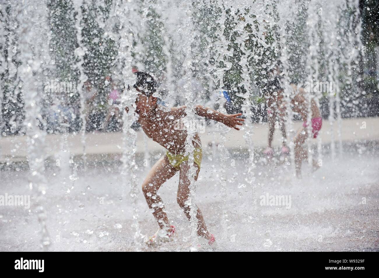 Junge chinesische Kinder spielen mit Wasser in einen Brunnen an einem heißen Tag in Wuhan City zu kühlen, Zentrale China Provinz Hubei, 29. Juni 2013. Nat Stockfoto