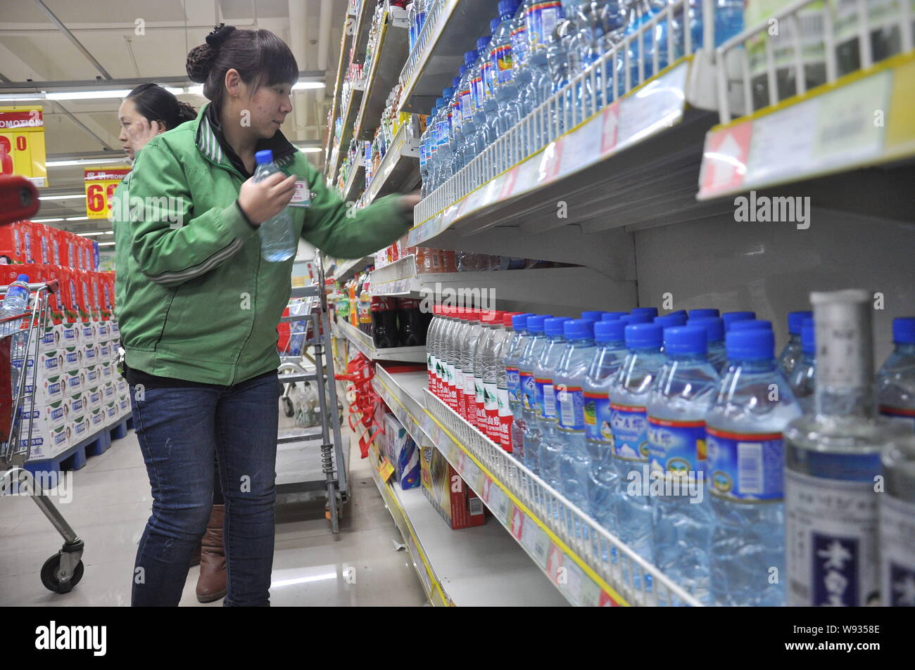 Ein chinesischer Mitarbeiter setzt Flaschen Mineralwasser auf dem Regal für Verkauf in einem Supermarkt nach dem Zhuozhang Fluss war verunreinigt durch Anilin gelangt durch ein Stockfoto