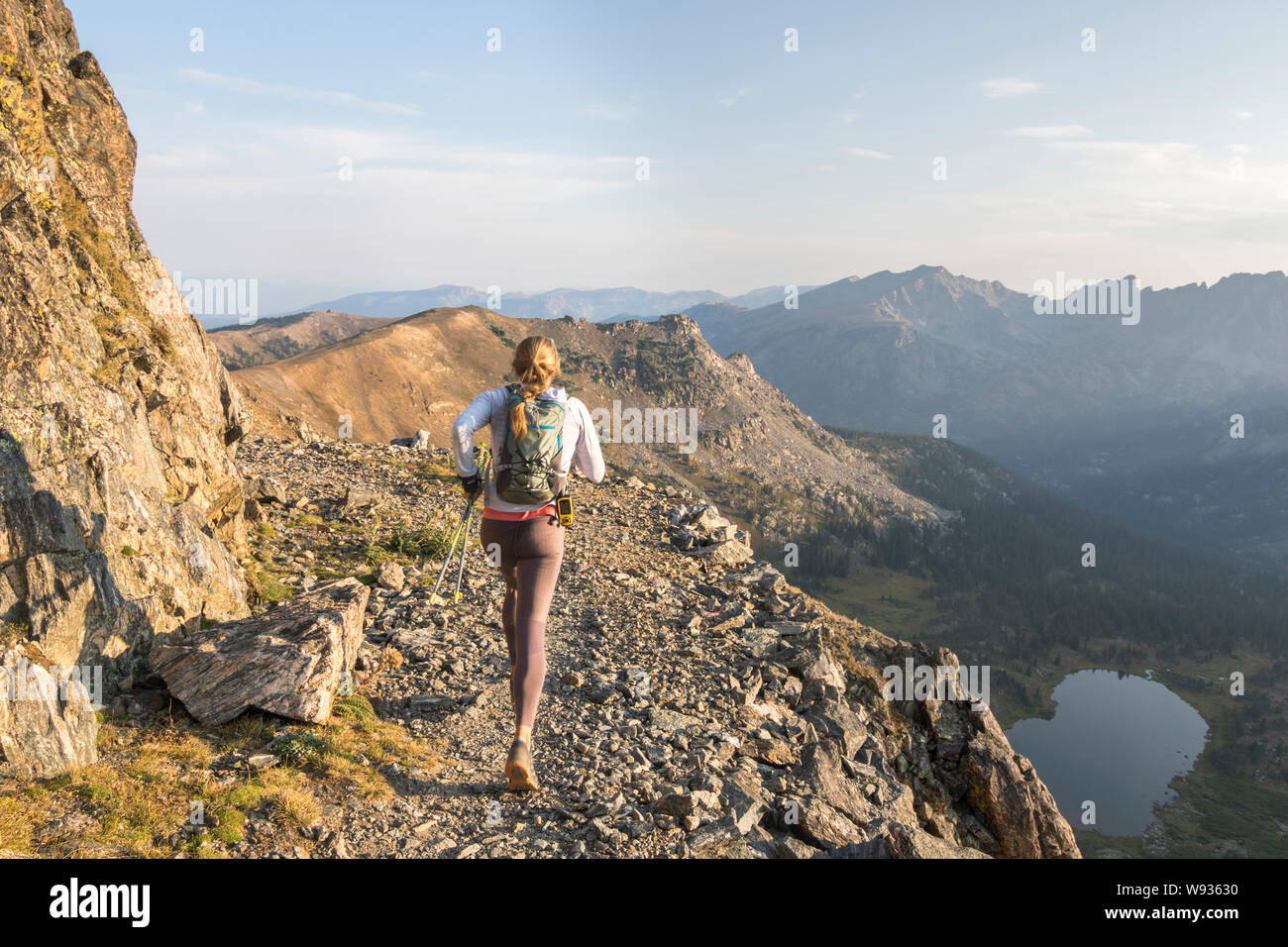 Eine junge Frau hat am frühen Morgen einen Trail Run hoch oben in den felsigen M Stockfoto