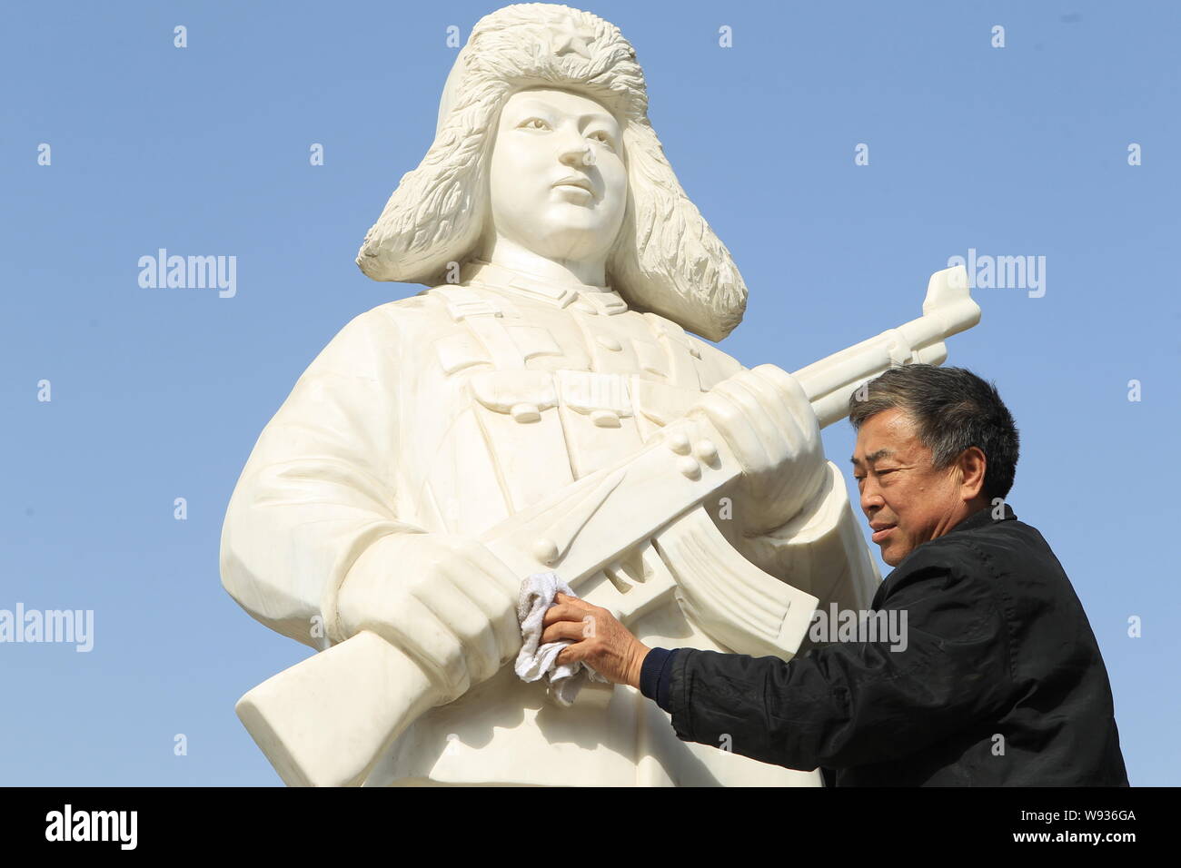 Ein Mann reinigt ein Fels gehauen Abbildung von Lei Fung (oder Lei Feng) in einem Park in Stadt Xuchang, Zentrale China Provinz Henan, 4. März 2013. Anfang März e Stockfoto