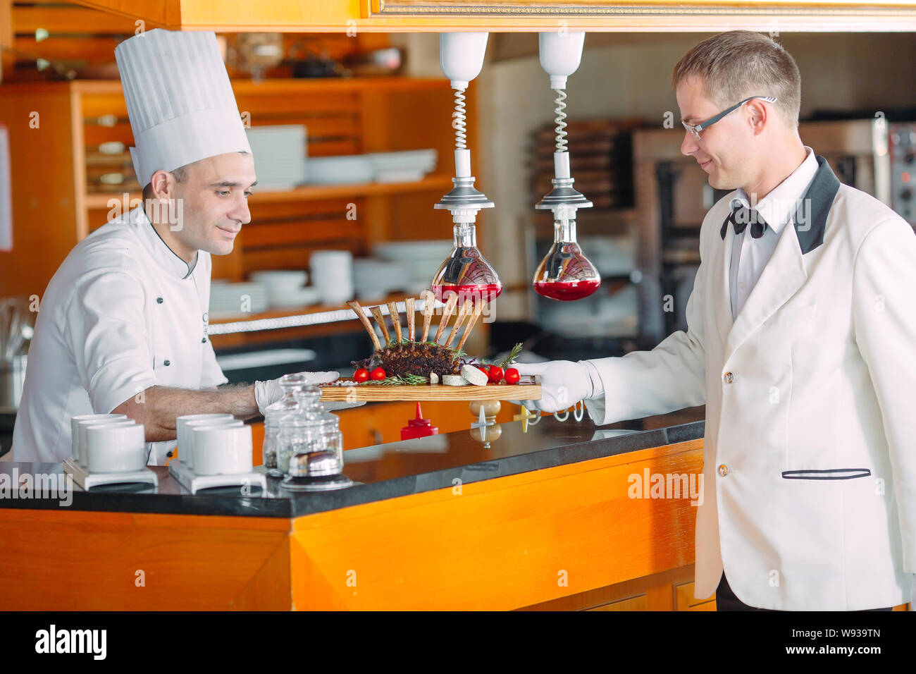 Der Koch leitet die Kellner das fertige Gericht. Lammrippchen. Stockfoto