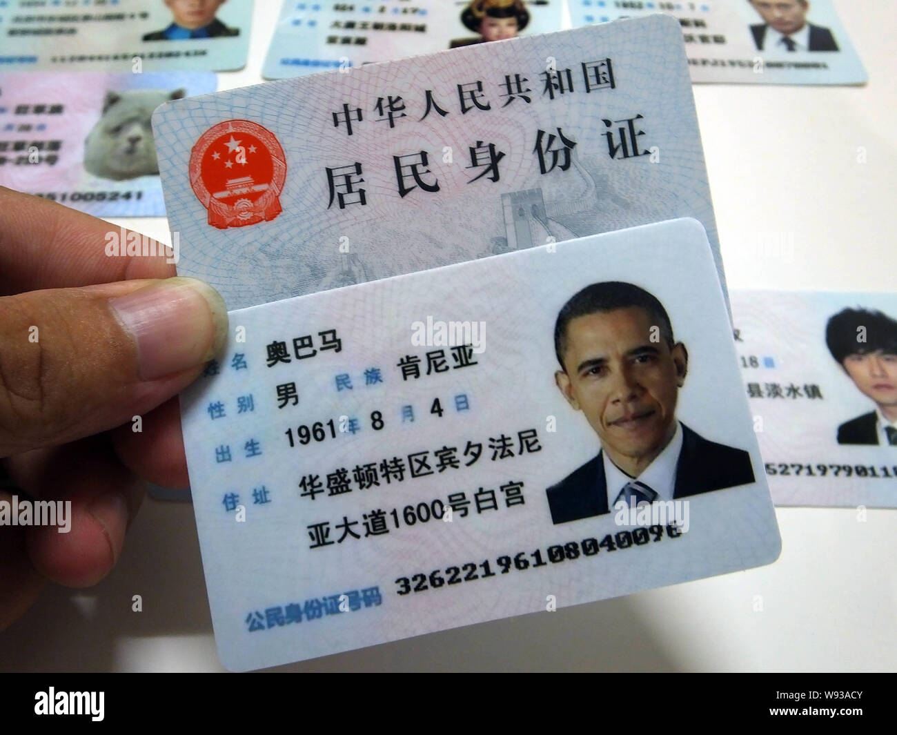 Ein Mann zeigt eine gefälschte Chinesischen ID-Karte von US-Präsident Barack Obama zum Verkauf an einen Stand auf einer Straße in Guangzhou City, South China Guangdong Provinz, Stockfoto