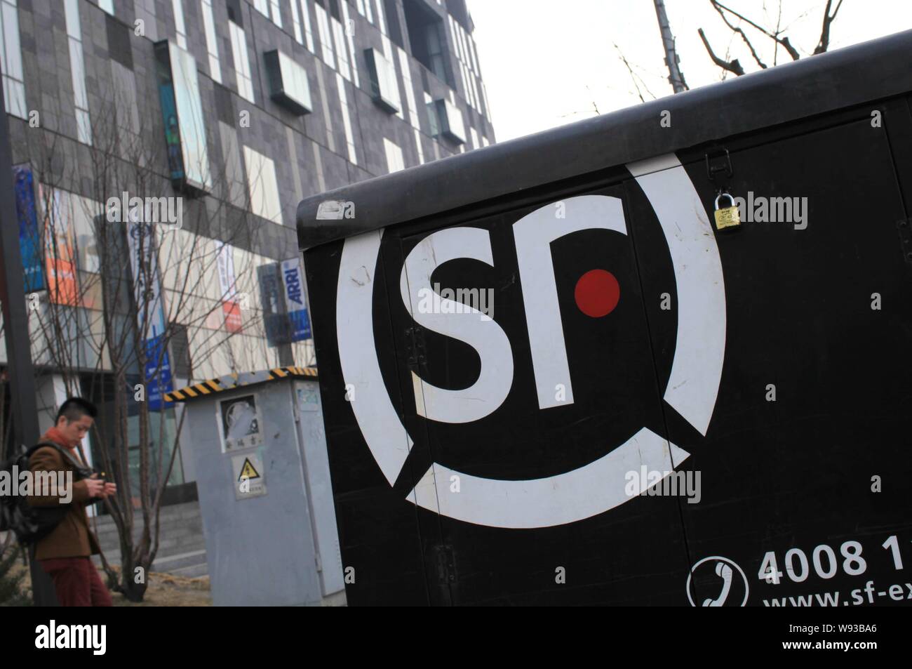 ---- Einen Fußgänger an ein Fahrzeug der SF Express auf einer Straße in Peking, China, 6. März 2013. Chinesische Private Equity Firma Citic Capital Holdi Stockfoto